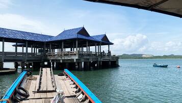 A pier with a covered structure, wooden deck, and a boat docked at the end.