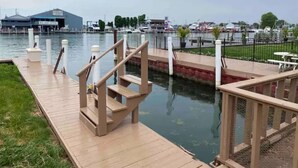 A wooden dock extending into a calm body of water with a marina in the background.