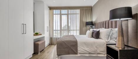 Un dormitorio moderno con cama, mesita de noche, lámpara y armario.