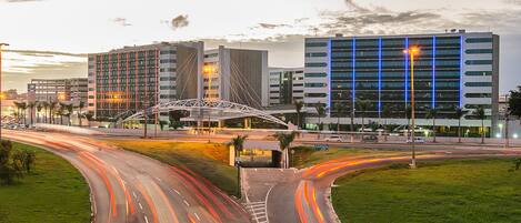 A multi-level parking structure with a modern design, surrounded by a well-maintained grassy area and a curved road with light trails indicating traffic flow.