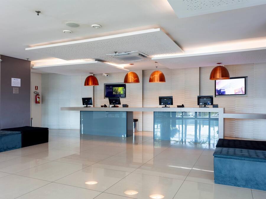A modern reception area with a clean, tiled floor, a reception desk, and three pendant lights.