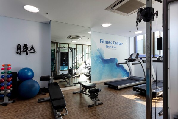 A fitness center with exercise equipment, a treadmill, and a wall with the text "Fitness Center WYNDHAM".