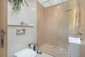 A modern bathroom with a shower, a toilet, and a sink.