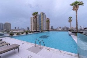 A rooftop swimming pool with a view of high-rise buildings and palm trees.