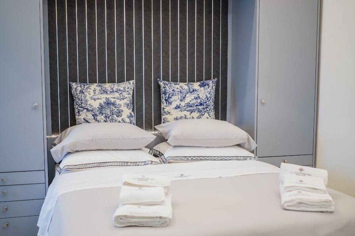A modern bedroom with a bed, two pillows, a hanging light fixture, and a wardrobe.