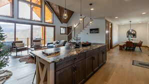 Une cuisine spacieuse dotée d’un grand îlot central, de meubles en bois et offrant une vue sur l’extérieur.