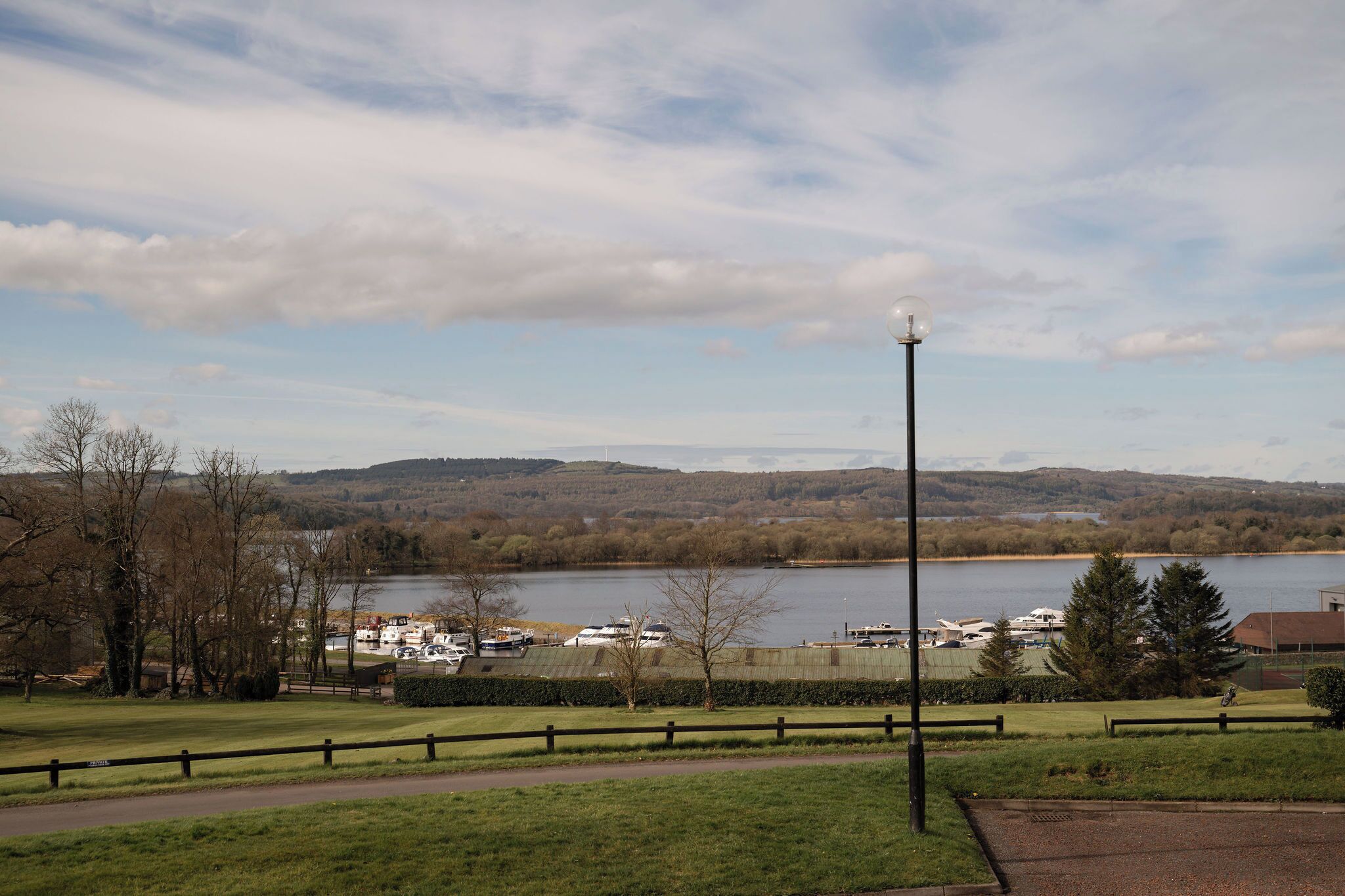Une vue sur un lac avec des bateaux, un sentier et une clôture.