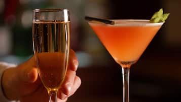 Two glasses of beverages on a wooden bar counter.