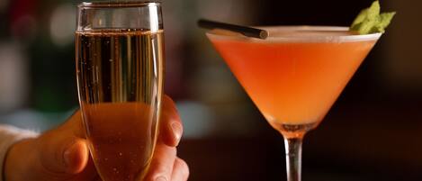 Two glasses of beverages on a wooden bar counter.