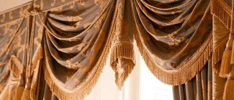 Una ventana con cortinas decorativas adornadas con flecos y un diseño ornamental.