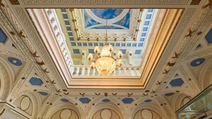An ornate ceiling with a chandelier, intricate moldings, and a skylight with a blue sky view. - Manor House Country Hotel (Enniskillen)