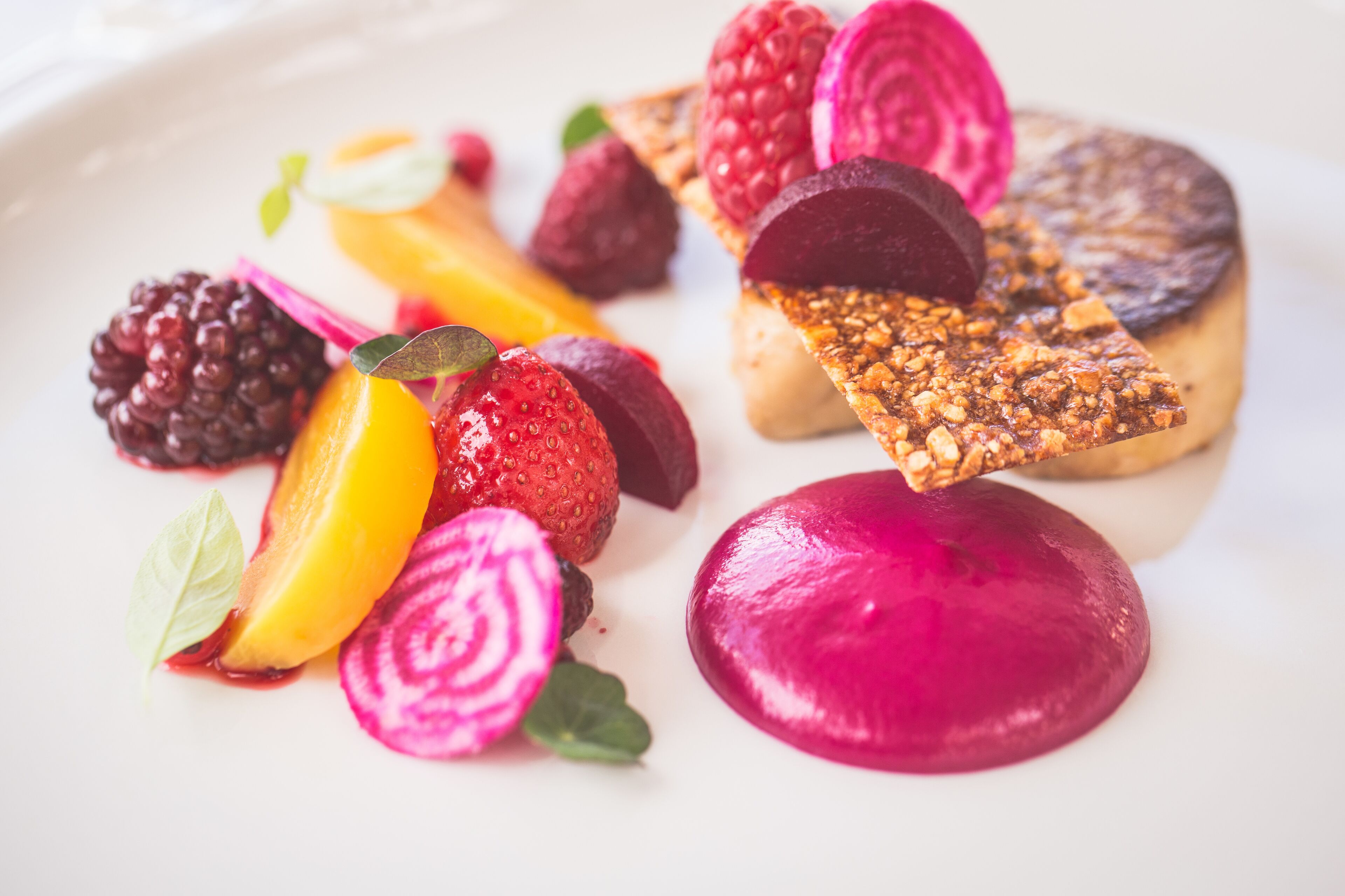 A plate of assorted fruits and a piece of bread with seeds.