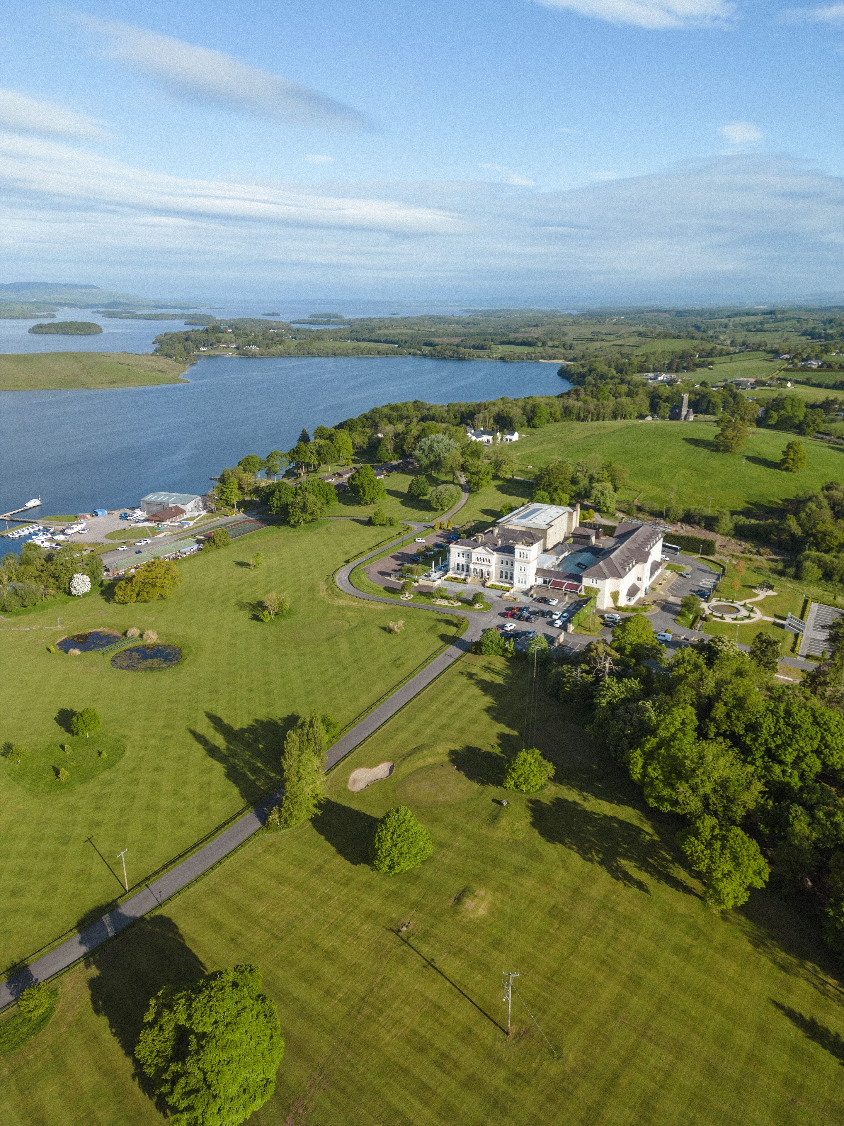 An aerial view of a property with a large building, a parking area, and a lake.