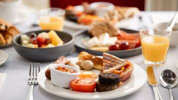 A breakfast setting with various dishes, including toast, eggs, tomatoes, and a glass of orange juice.