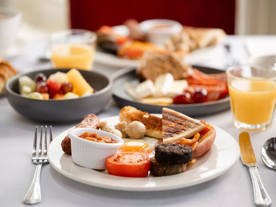 A breakfast setting with various dishes, including toast, eggs, tomatoes, and a glass of orange juice.