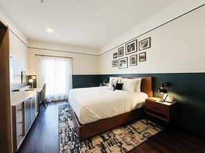 A modern hotel room with a large bed, a desk, and a chair.