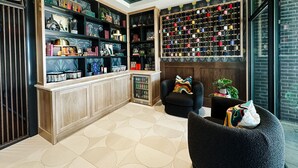 A cozy reading nook with a bookshelf, a large spool of thread, and a comfortable chair. - The Carpentry Hotel (Dalton)