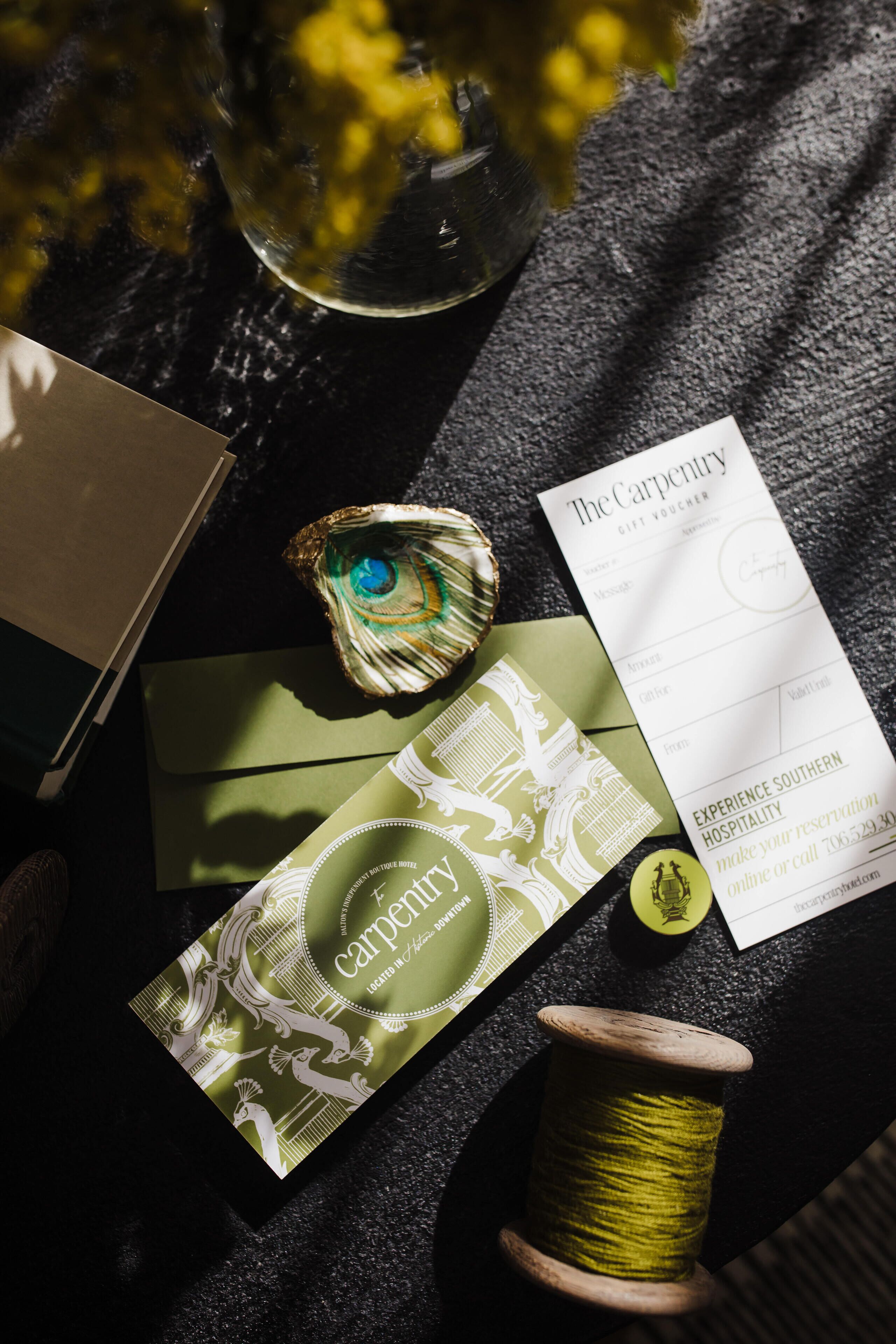 A table with a gift voucher, a card, a spool of thread, and a decorative item.