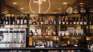 A bar area with shelves of liquor bottles, a coffee machine, and bar tools. - The Carpentry Hotel (Dalton)