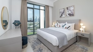 Quarto moderno com uma cama grande, uma escrivaninha e vista para a paisagem urbana através de grandes janelas.