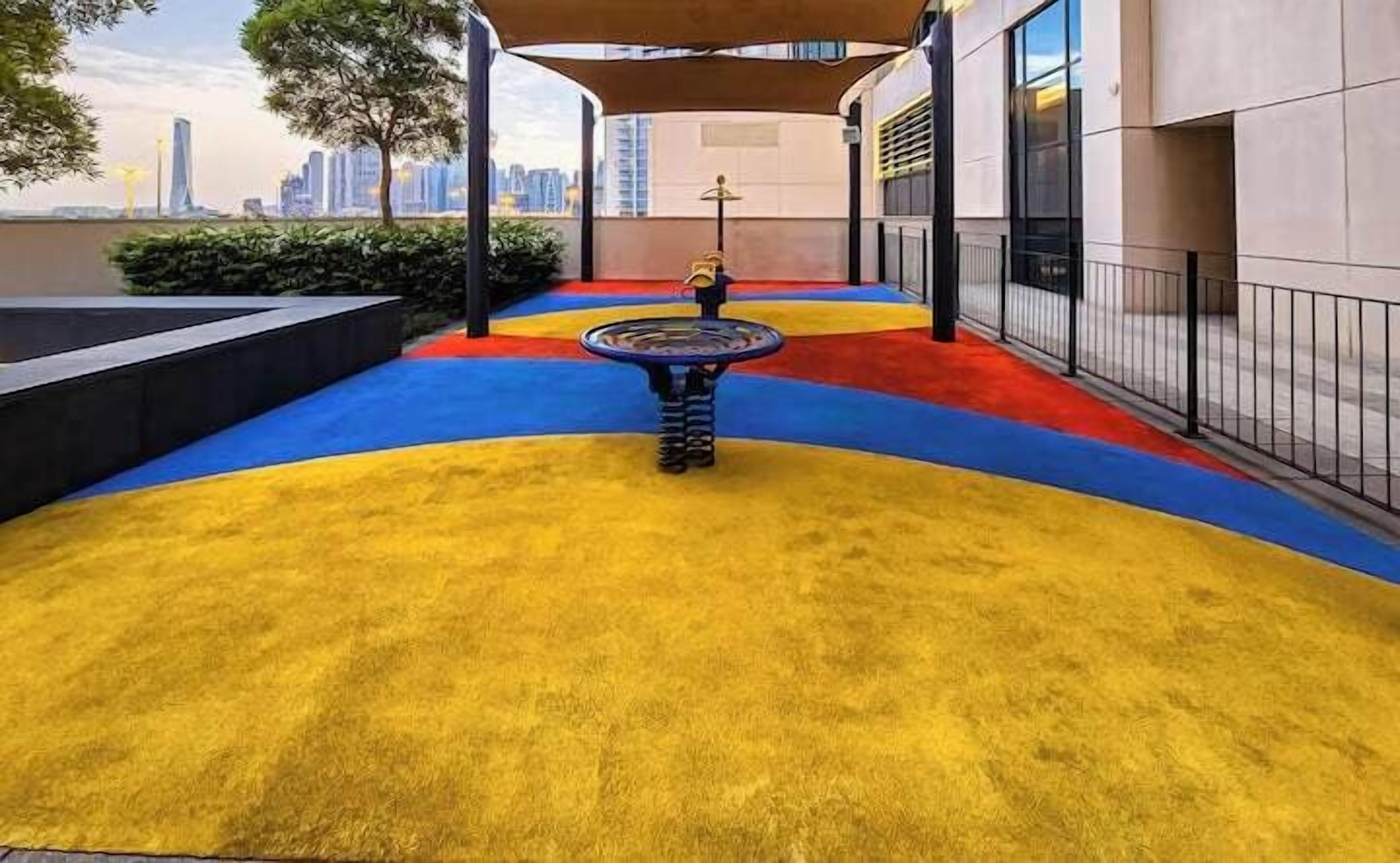 Ein Spielplatz mit bunten Gummibodenbelägen und einer Spielanlage in der Mitte.