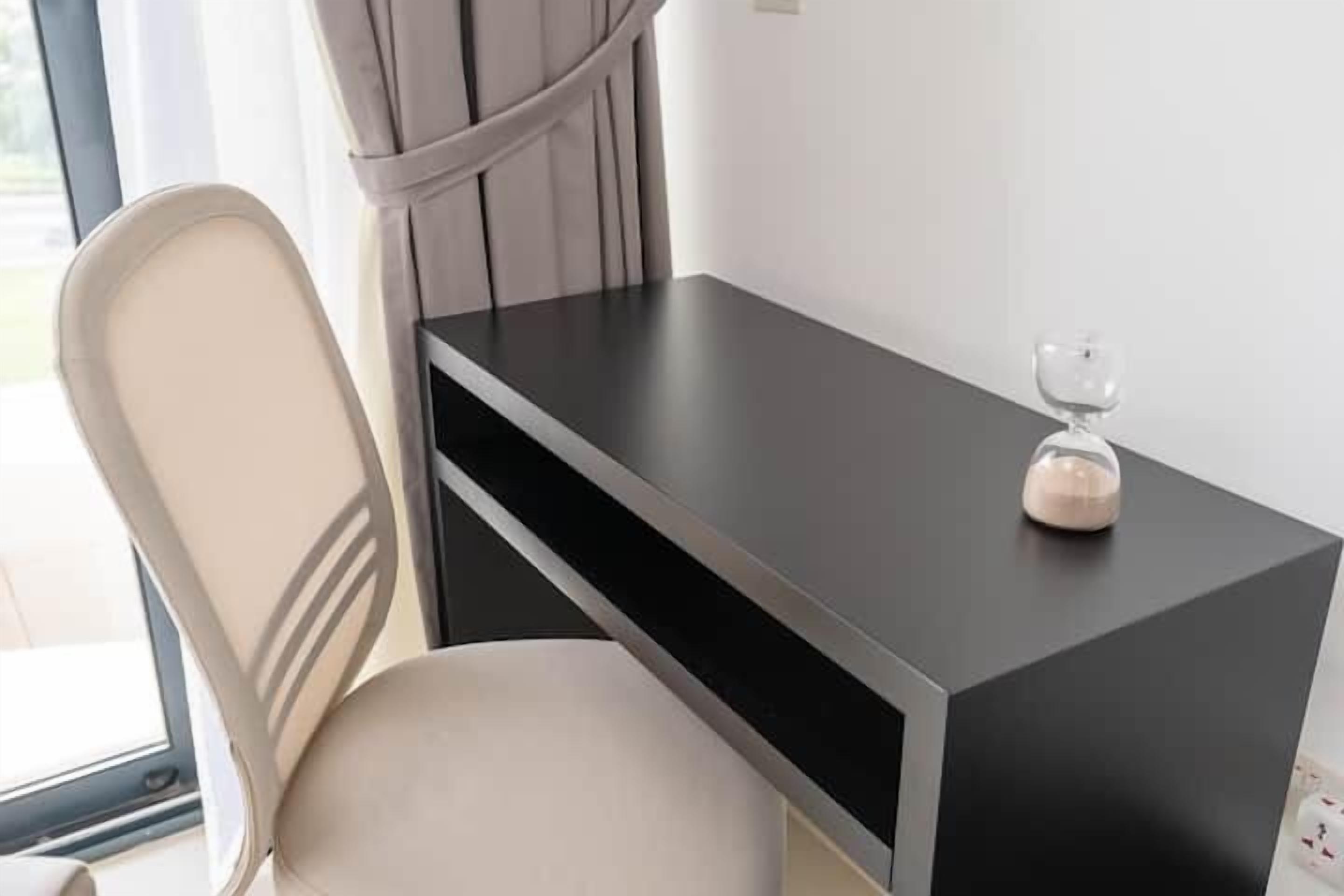 A modern room with a black desk, a white chair, and a window with curtains.