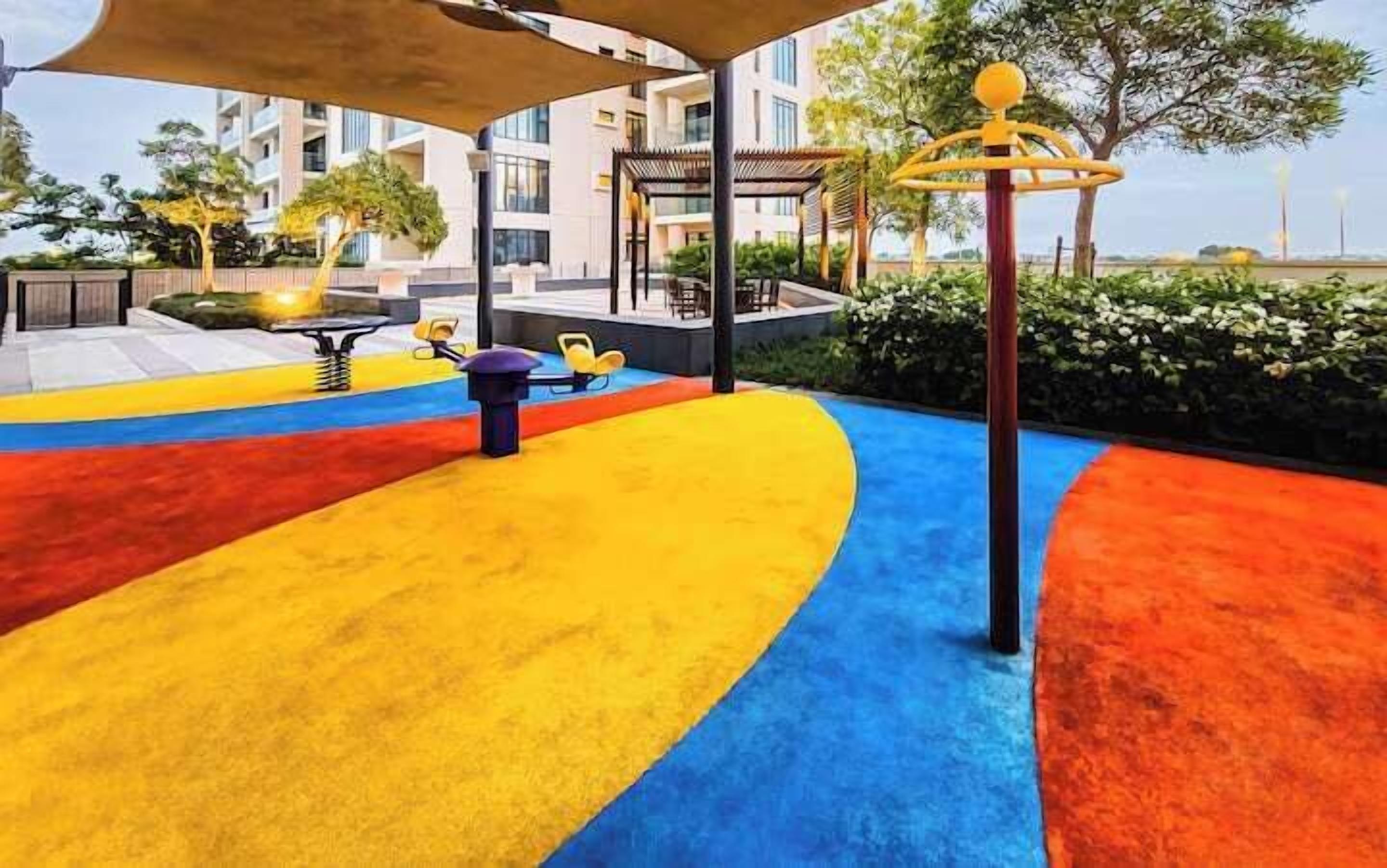 Un'area giochi con zone colorate e un edificio sullo sfondo.