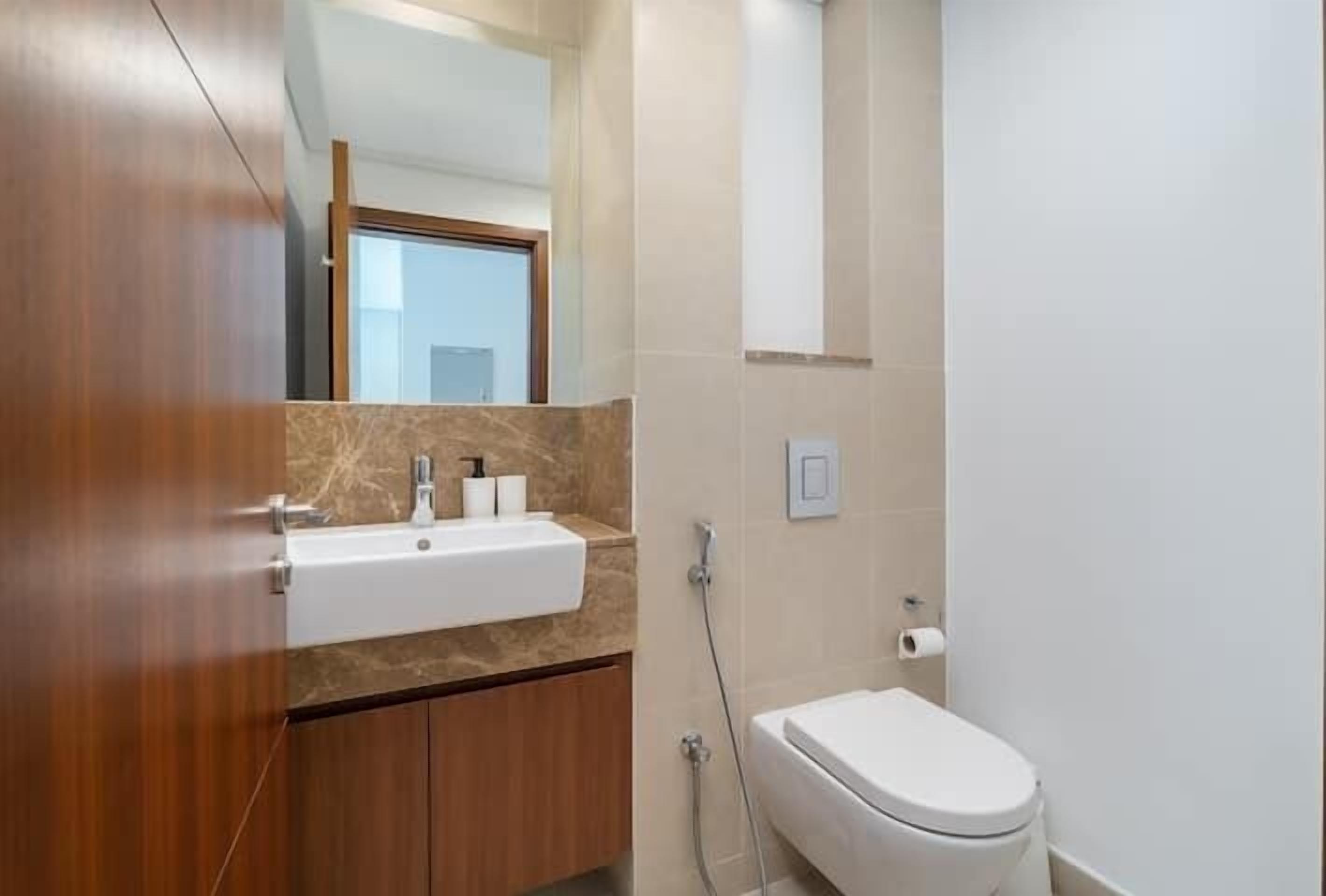 A bathroom with a wooden vanity, a white sink, and a toilet.