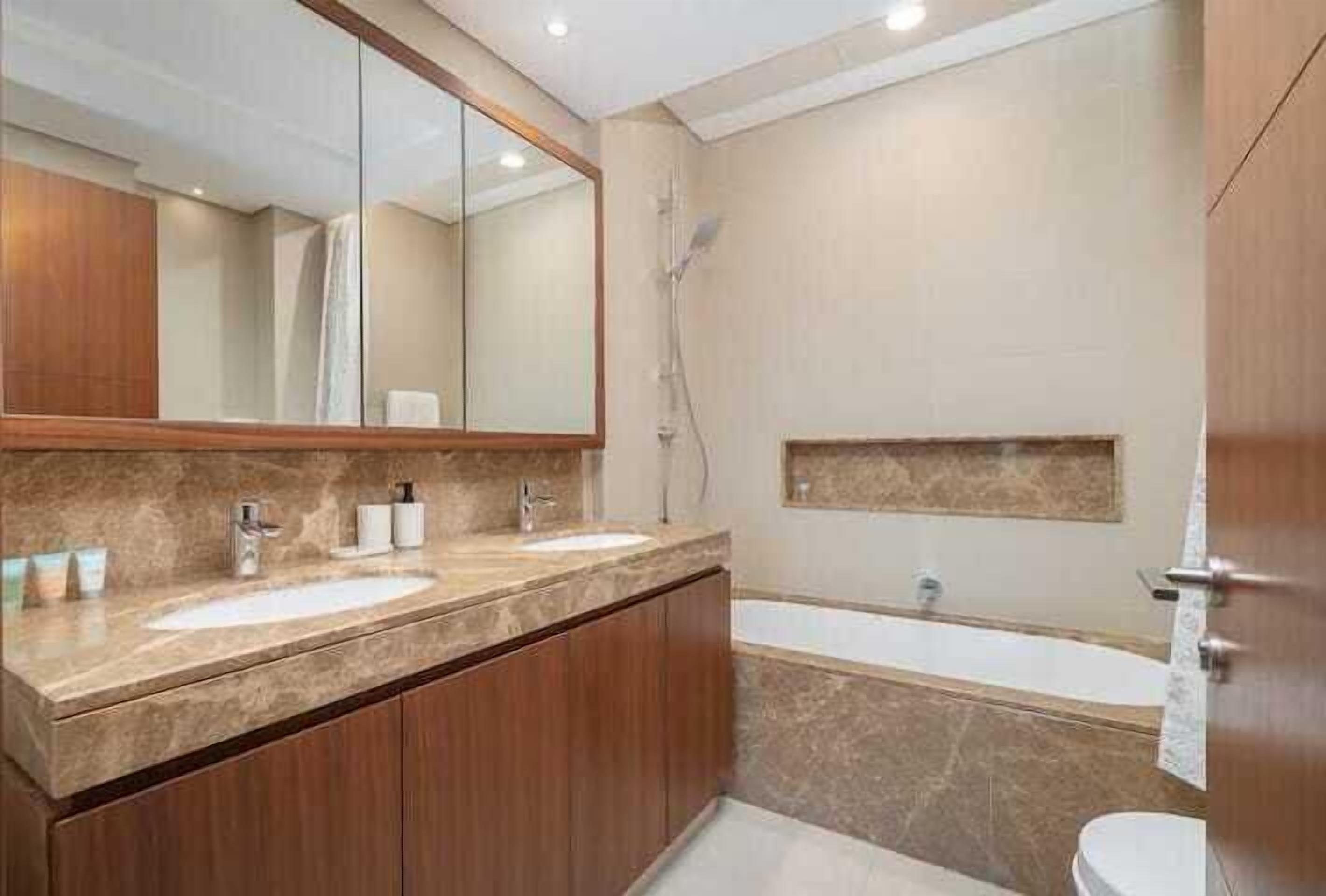 Een badkamer met twee wasbakken, een grote spiegel, een douche en een bad.