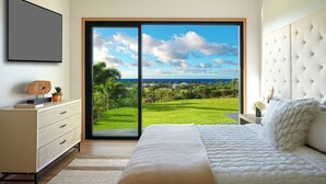 Quarto com uma cama grande, cômoda e porta de vidro deslizante para uma paisagem verde.
