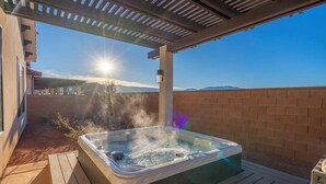 Ein Whirlpool unter einer Pergola mit freiem Blick auf Berge im Hintergrund.