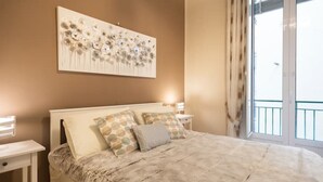 Un dormitorio con una cama grande, una mesita de noche, una obra de arte en la pared y una ventana con vistas.