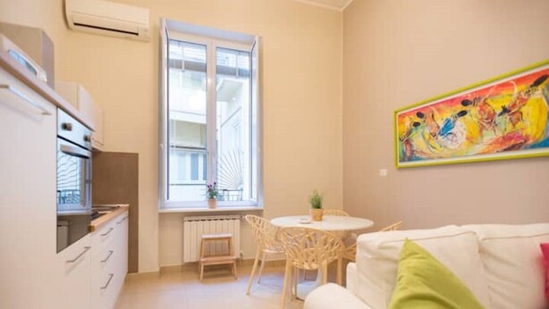 Un espacio habitable compacto con kitchenette, comedor y sofá.