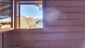 A wooden cabin with a window overlooking a mountainous landscape.