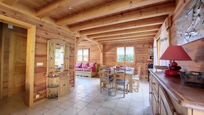A wooden cabin interior with a dining area, a sofa, and a kitchen counter.