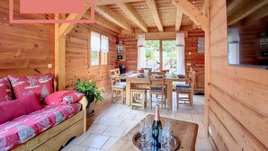 A cozy wooden cabin interior with a sofa, dining table, and a champagne bottle on a tray.
