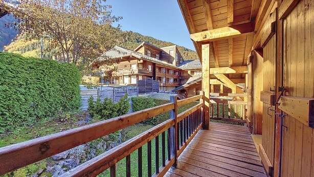 A wooden chalet with a balcony overlooking a mountainous area.
