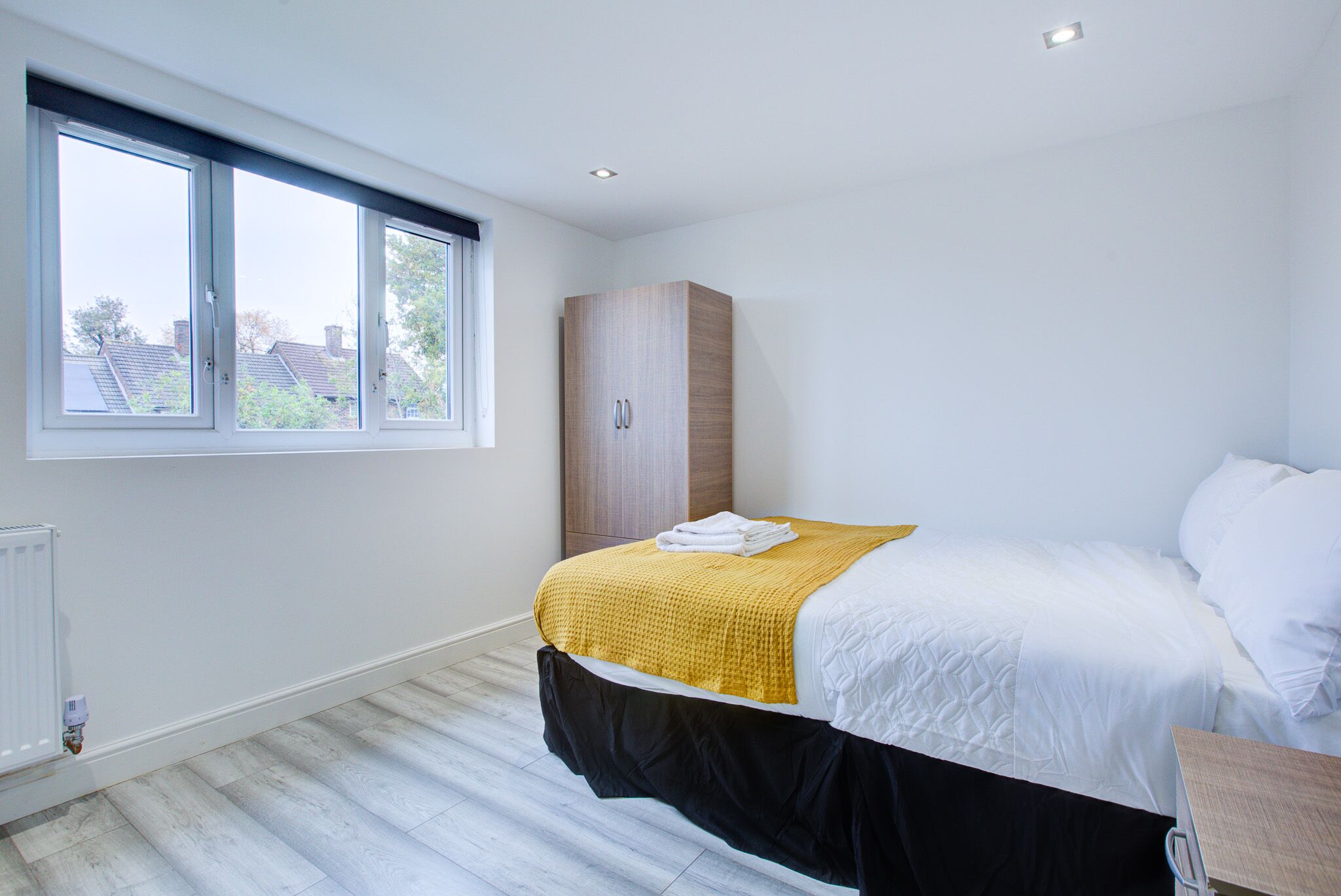 A bedroom with a bed, a wardrobe, and a window.