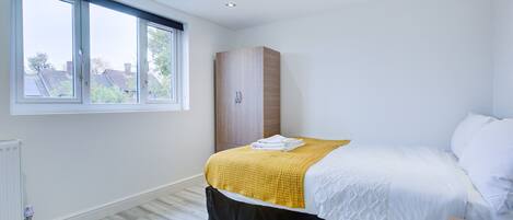 A bedroom with a bed, a wardrobe, and a window.
