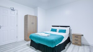Una camera da letto con un letto, un armadio, un comodino e una porta.