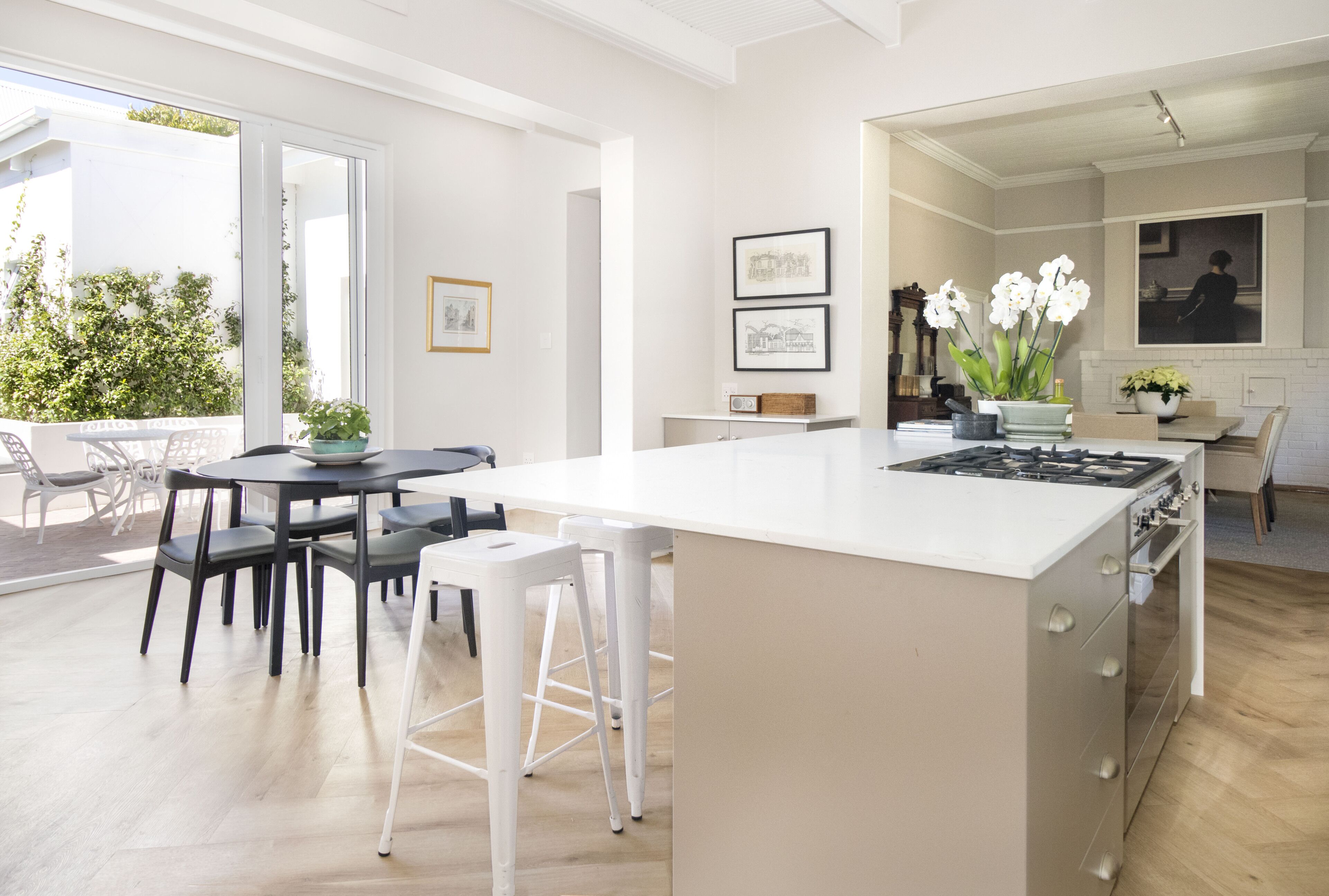 Een moderne keuken met een centraal eiland, witte kasten en een eethoek met een tafel en stoelen.