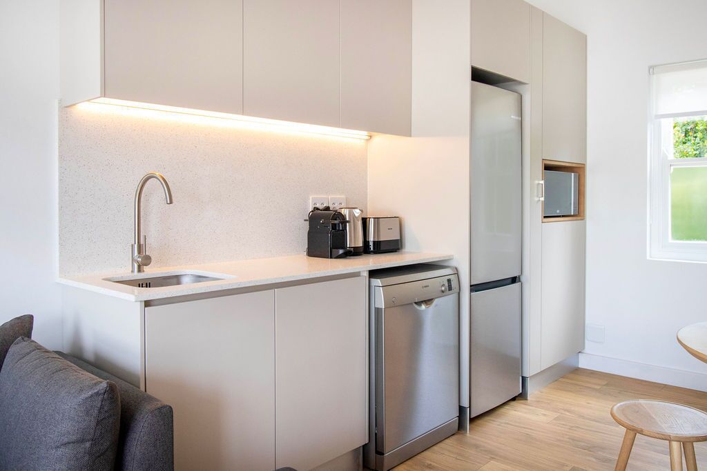 A modern kitchen with a dishwasher, a built-in oven, and a coffee maker.