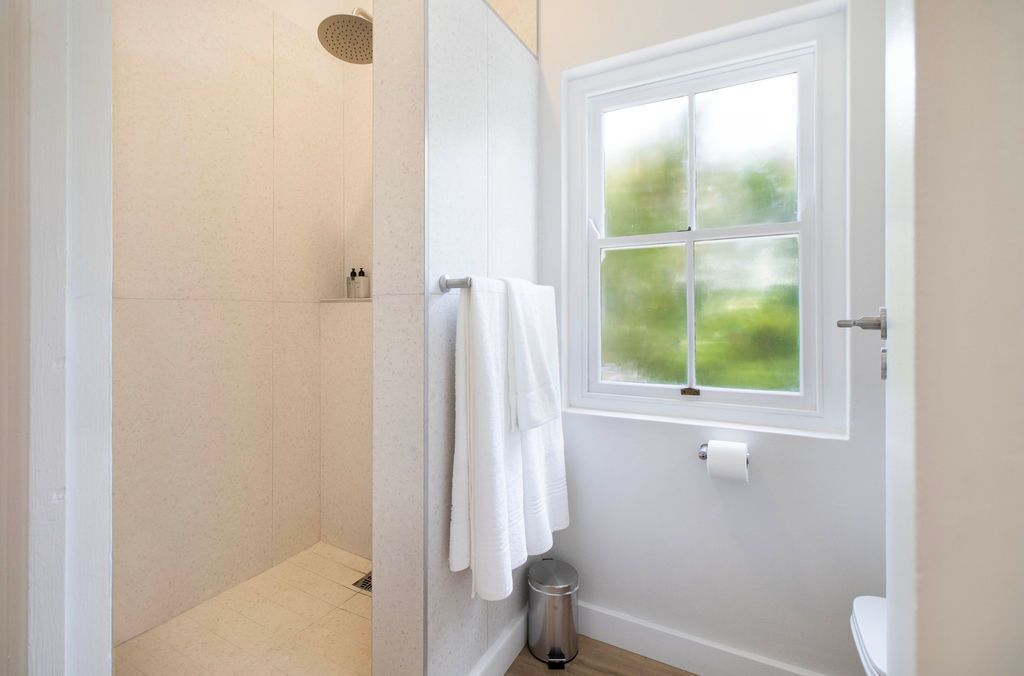 Une salle de bain avec une douche, des toilettes et une fenêtre.