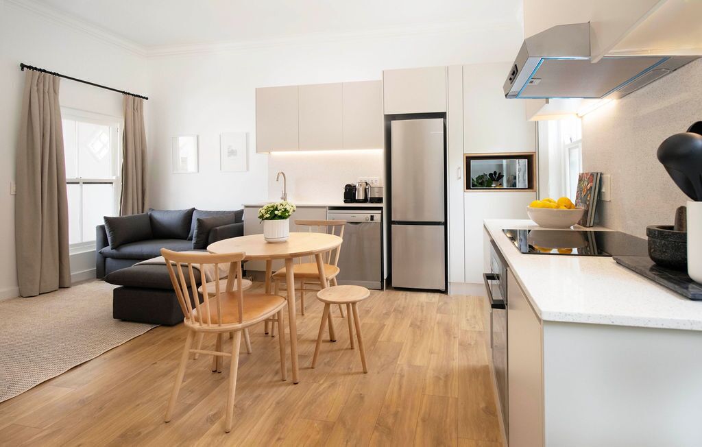 A modern kitchen with a dining area, a sofa, and a coffee machine.