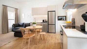 A modern kitchen with a dining area, a sofa, and a coffee machine.