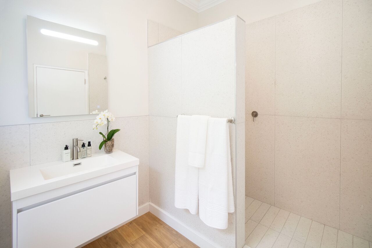 Une salle de bain moderne avec un lavabo blanc, un miroir et une douche.