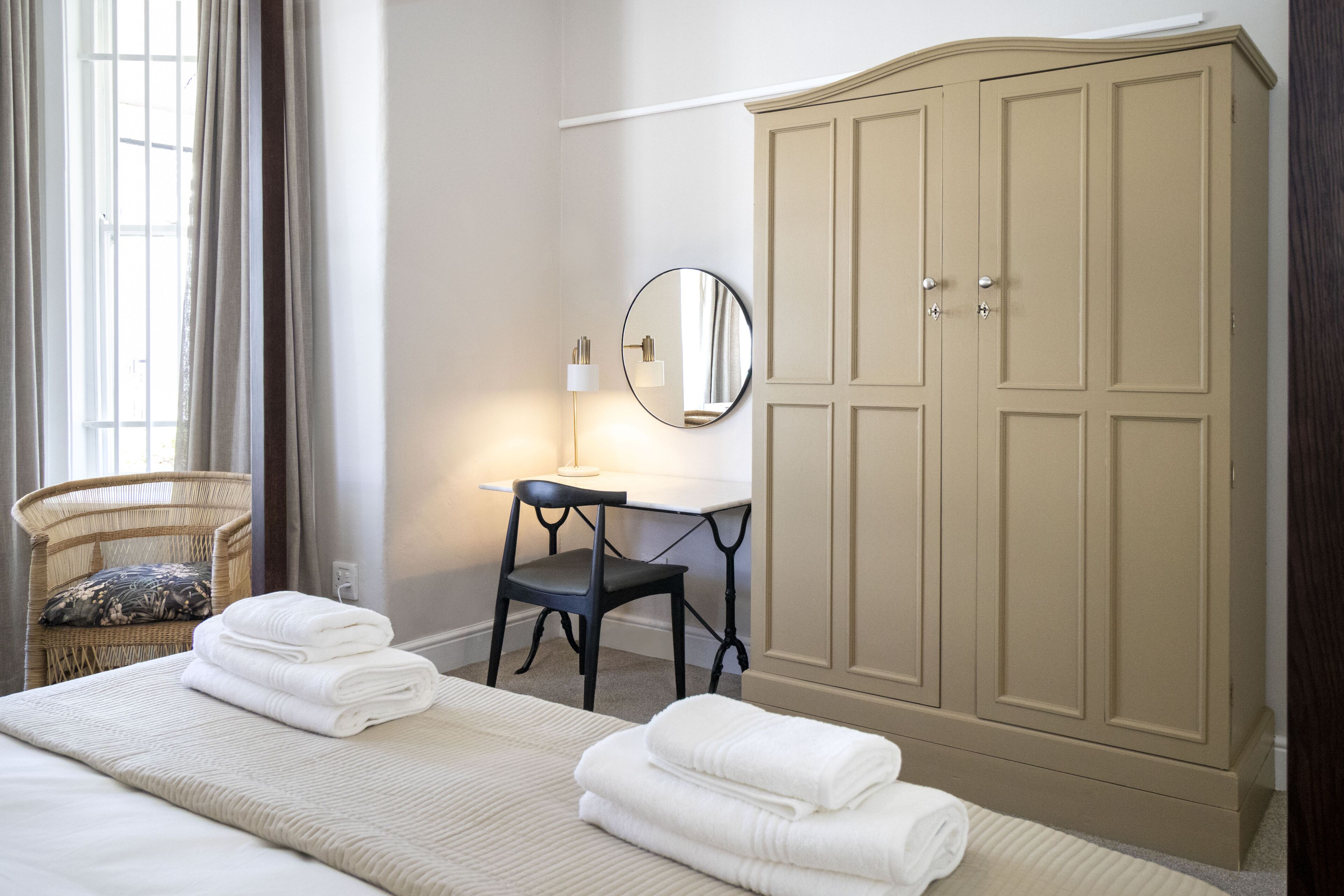 Ein Hotelzimmer mit Bett, Stuhl, Schreibtisch, Kleiderschrank und Spiegel.