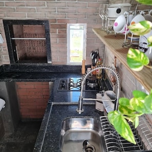A compact kitchen with a gas stove, a sink, and a brick oven. - O Chale Encantado (Rancho Queimado)