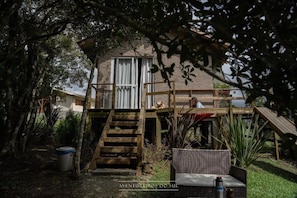 A rustic wooden house with a balcony, surrounded by lush greenery. - O Chale Encantado (Rancho Queimado)