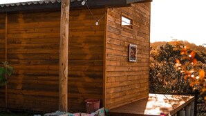 A wooden cabin with a sloped roof, a chimney, and a small window. - O Chale Encantado (Rancho Queimado)